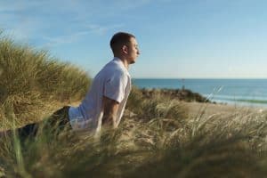Outdoor fitness portrait photography in Dorset of a male yoga teacher practicing yoga on a beach at sunrise