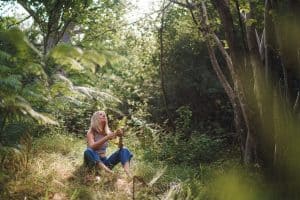 Full-body outdoor portrait photography in Dorset of a woman Forest bathing in a New woodland clearing with sunlight filtering through the canopy in The New Forest