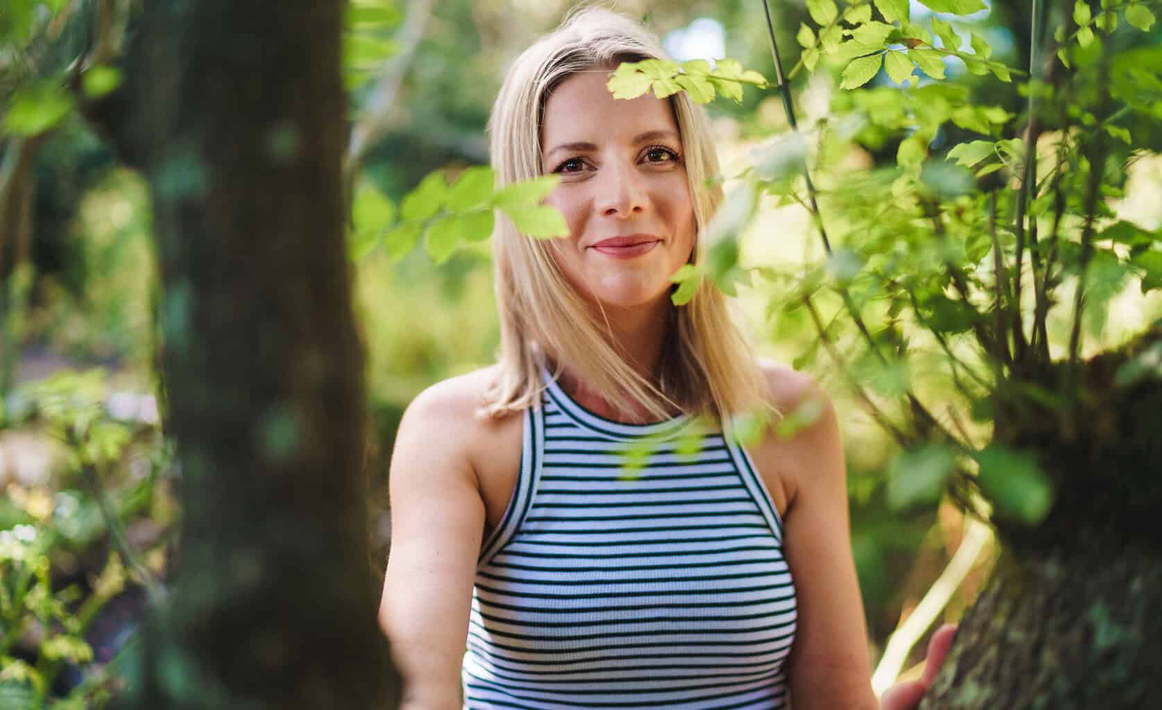 Relaxed portrait of a woman smiling in woodland in the New Forest, Hampshire.