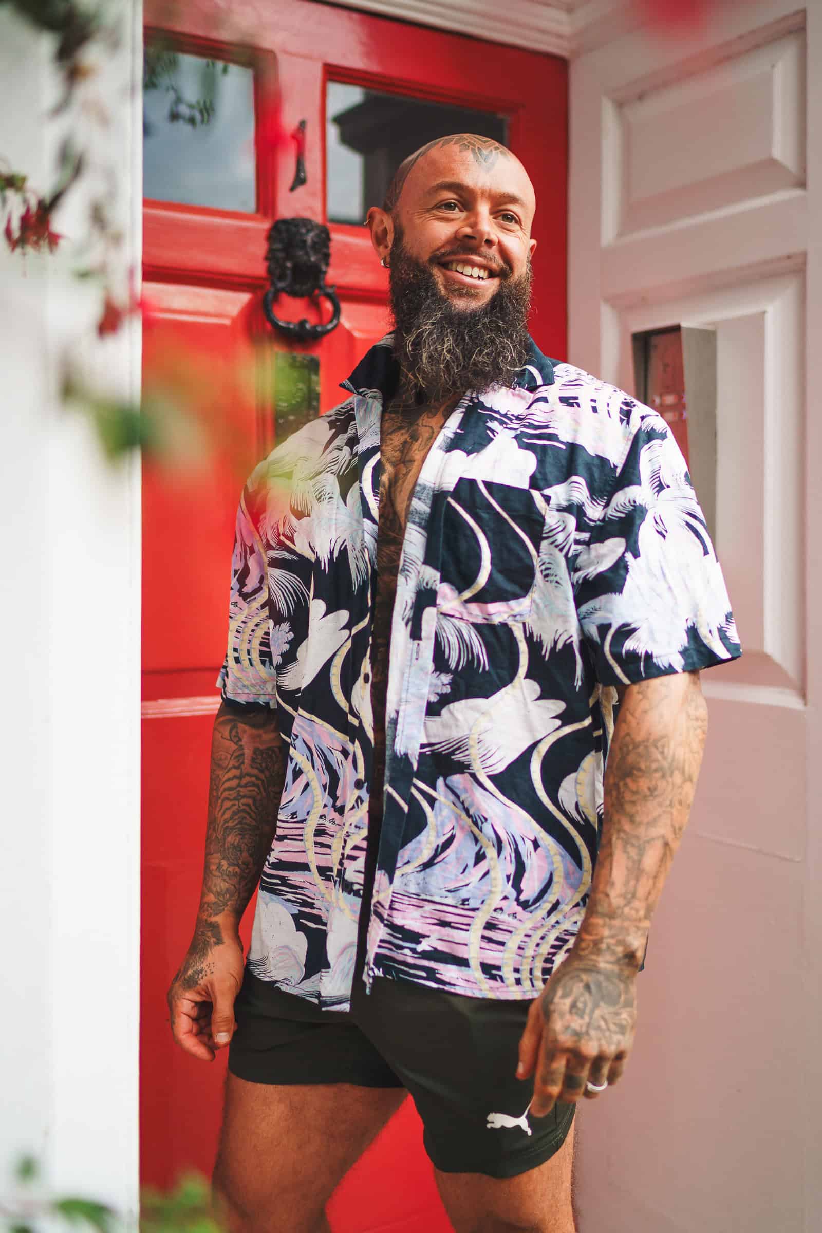 Happy man stands by red front door for personal branding photo in Bournemouth