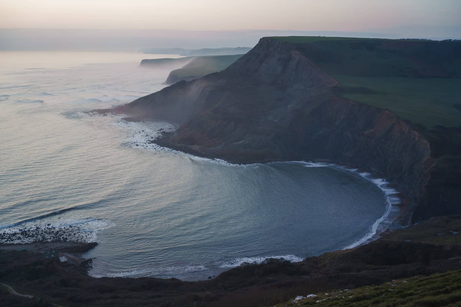 landscape in Dorset featuring sea cliffs at dusk with dramatic coastline and natural light